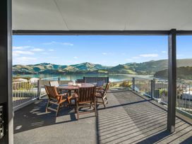 An outdoor patio with a table and chairs overlooking a scenic view at Belle Vue in Akaroa
