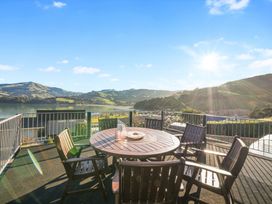 An outdoor area with a table and chairs overlooking a lake at Belle Vue in Akaroa
