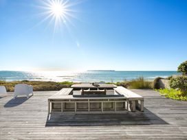 An outdoor dining area with a table and benches at Sandbanks, Papamoa Holiday Home, Papamoa