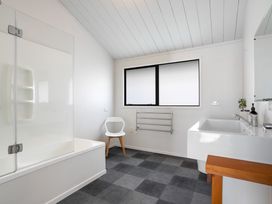 A bathroom with a bathtub, shower, sink and towel rack at Sandbanks, Papamoa Holiday Home, Papamoa