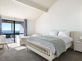 A bedroom with two beds and a view of the water at Sandbanks, Papamoa Holiday Home