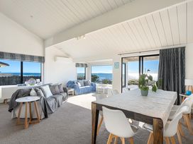 A living room with a sofa and dining table at Sandbanks, Papamoa Holiday Home, Papamoa