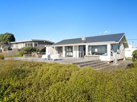 A house with a deck and chairs at Sandbanks, Papamoa Holiday Home in Papamoa