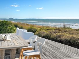 An outdoor area with chairs and a table alongside the ocean at Sandbanks, Papamoa Holiday Home, Papamoa