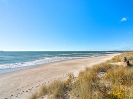 A beach with sand and ocean waves at Sandbanks, Papamoa Holiday Home in Papamoa