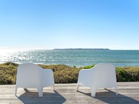 Two white chairs facing the sea at Sandbanks, Papamoa Holiday Home, Papamoa