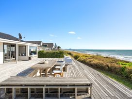An outdoor deck with a table and chairs at Sandbanks, Papamoa Holiday Home in Papamoa