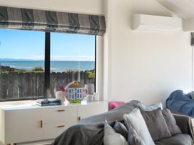 A living room with a view of the ocean and decorative items at Sandbanks, Papamoa Holiday Home