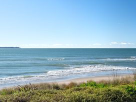 An ocean view with sand and vegetation at Sandbanks, Papamoa Holiday Home in Papamoa