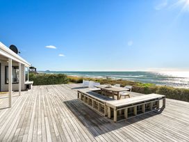 A deck with a table and chairs overlooking the ocean at Sandbanks, Papamoa Holiday Home in Papamoa
