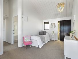 A bedroom with a bed and a nightstand at Sandbanks, Papamoa Holiday Home, Papamoa