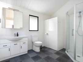 A bathroom with a sink, toilet, shower, and mirror at Sandbanks, Papamoa Holiday Home in Papamoa