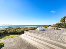 An outdoor area with a deck and chairs overlooking the sea at Sandbanks, Papamoa Holiday Home in Papamoa