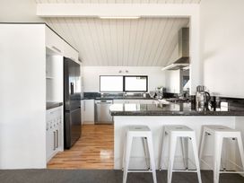 A kitchen with appliances and stools at Sandbanks, Papamoa Holiday Home in Papamoa