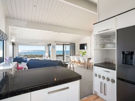 A living room and kitchen area with a view of the water at Sandbanks, Papamoa Holiday Home, Papamoa