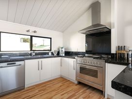 A kitchen with dishwasher, oven, and sink at Sandbanks, Papamoa Holiday Home Papamoa
