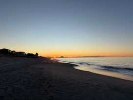 A beach during sunset with houses in the background at Sandbanks - Papamoa Holiday Home Papamoa
