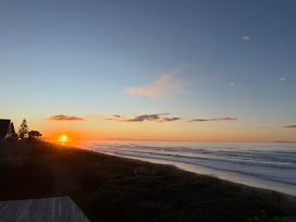 A sunset over the ocean beach at Sandbanks - Papamoa Holiday Home, Papamoa