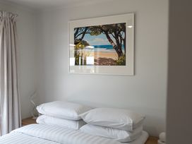 A bedroom with bed and framed artwork at Calden Cottage - Ngurunguru Holiday Home