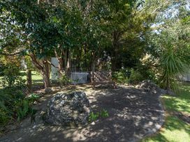A garden with a bench and trees at Calden Cottage - Ngurunguru Holiday Home Ngunguru