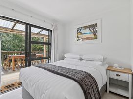 A bedroom with a bed and sliding door leading to a deck at Calden Cottage - Ngurunguru Holiday Home Ngunguru
