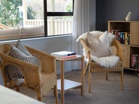 A living room with two chairs, a table, and a bookshelf at Calden Cottage - Ngurunguru Holiday Home Ngunguru