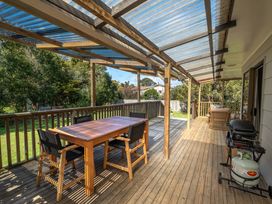 An outdoor area with a wooden table and chairs at Calden Cottage - Ngurunguru Holiday Home in Ngunguru