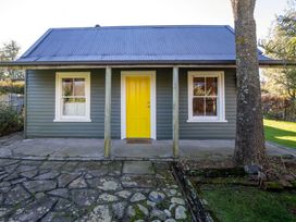 A house exterior with a yellow door and windows at Thimble Cottage, Ashburton Holiday Home in Methven