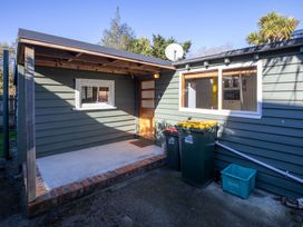 An outdoor area with a door, window, and garbage bins at Thimble Cottage, Ashburton Holiday Home in Methven