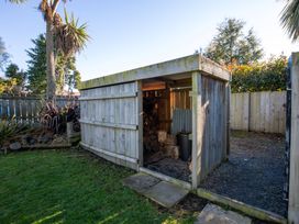 A wooden shed storing firewood in a garden at Thimble Cottage, Ashburton Holiday Home, Methven