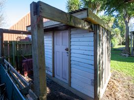 A wooden shed with a door in a garden at Thimble Cottage, Ashburton Holiday Home in Methven