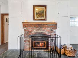 A living room with a fireplace and wall cabinets at Thimble Cottage, Ashburton Holiday Home Methven