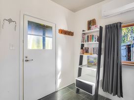 An entryway with a door, a shelf with books, and a window at Thimble Cottage, Ashburton Holiday Home, Methven