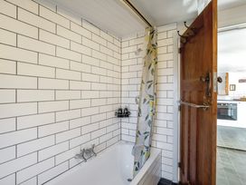 A bathroom with a bathtub and shower curtain at Thimble Cottage, Ashburton Holiday Home, Methven