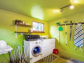 A laundry room with a washing machine and cleaning supplies at Thimble Cottage, Ashburton Holiday Home, Methven