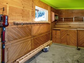 A shed with wooden workbench and storage cabinets at Thimble Cottage, Ashburton Holiday Home, Methven