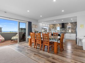 A kitchen with a dining area and sliding door at Seaside Escape - Ruakaka Holiday Home in Ruakaka