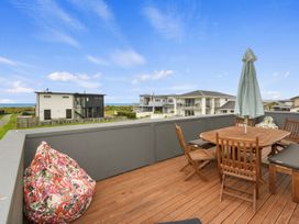 A roof terrace with a dining table and seating at Seaside Escape - Ruakaka Holiday Home Ruakaka