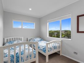 A bedroom with two beds and windows at Seaside Escape - Ruakaka Holiday Home Ruakaka
