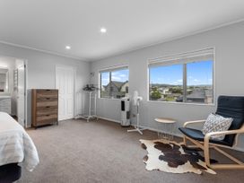 A bedroom with a bed, chair, and window view at Seaside Escape - Ruakaka