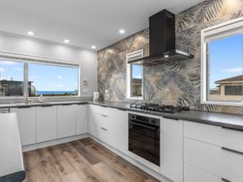 A kitchen with cabinets and appliances at Seaside Escape - Ruakaka Holiday Home in Ruakaka
