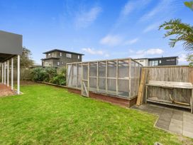 A garden with a greenhouse and outdoor sink at Seaside Escape - Ruakaka Holiday Home in Ruakaka