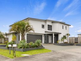 A house with a garage and palm trees at Seaside Escape - Ruakaka Holiday Home Ruakaka