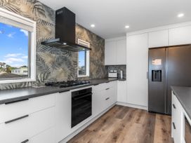 A kitchen with appliances and windows at Seaside Escape - Ruakaka Holiday Home in Ruakaka