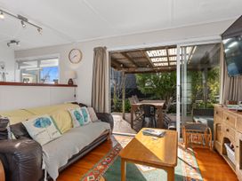 A living room with a sofa and sliding door leading to an outdoor area at Coastal Hideaway - Waipu Cove Holiday Home, Waipu