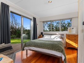 A bedroom with a bed and dresser at Coastal Hideaway - Waipu Cove Holiday Home, Waipu
