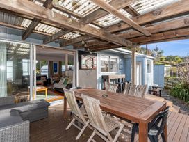 An outdoor area with a dining table and dartboard at Coastal Hideaway - Waipu Cove Holiday Home, Waipu