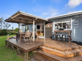 An outdoor area with a deck and dining furniture at Coastal Hideaway - Waipu Cove Holiday Home, Waipu