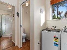 A bathroom with a shower and washing machine at Coastal Hideaway - Waipu Cove Holiday Home, Waipu