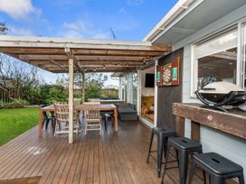 An outdoor area with a dining table and darts board at Coastal Hideaway - Waipu Cove Holiday Home, Waipu